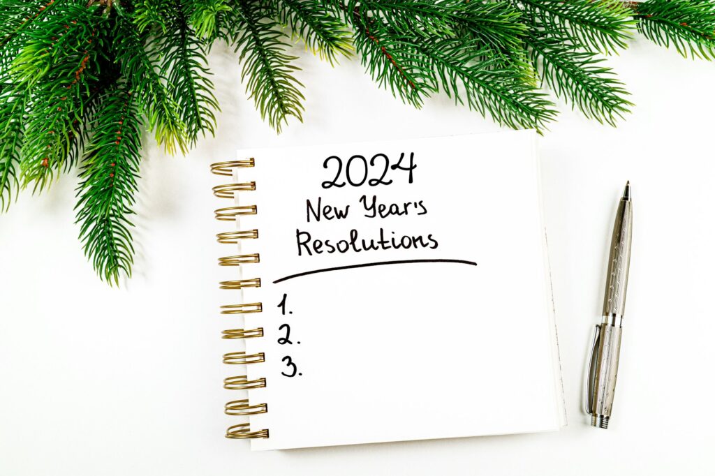 New year resolutions 2024 on desk. 2024 goals list with notebook, christmas tree on white background